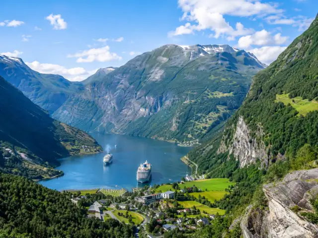 El fiordo de Geiranger entre montañas verdes, con dos cruceros en el agua