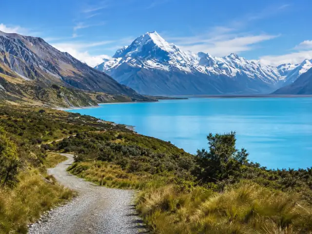 Un camino junto al lago Pukaki con el monte Cook nevado al fondo